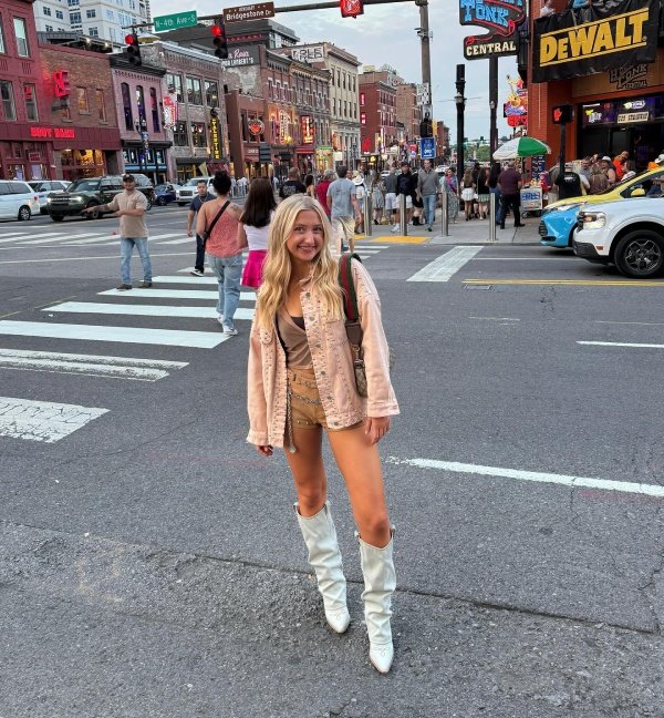 Woman wearing jacket, brown shorts and white boots. Nashville outfit inspo, country look