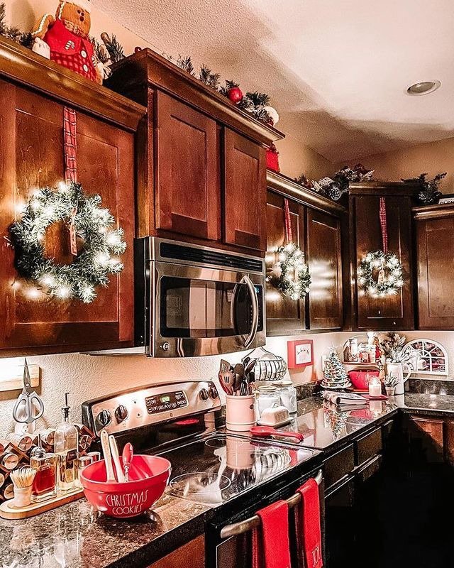 Small wreath with light hanging on kitchen cabinets and Christmas decorating above kitchen cabinets