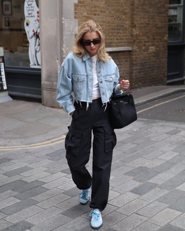 Youthful outfit featuring a cropped denim jacket, black cargo pants, and white sneakers