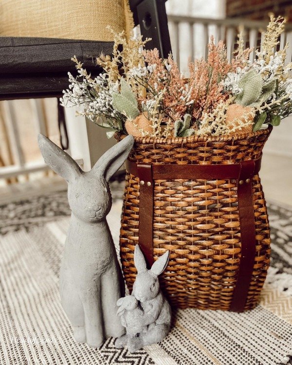 A wicker chair with a floral cushion and a wooden side table on a porch.