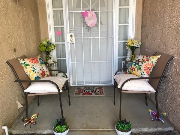 Outdoor pillows with floral patterns arranged on a porch bench.