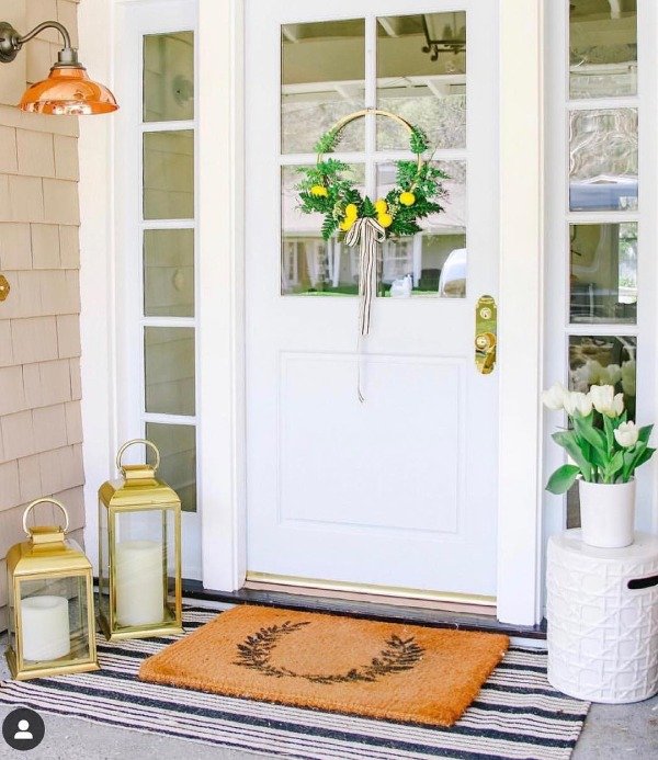 Metal lanterns with flickering candles placed on a porch railing.