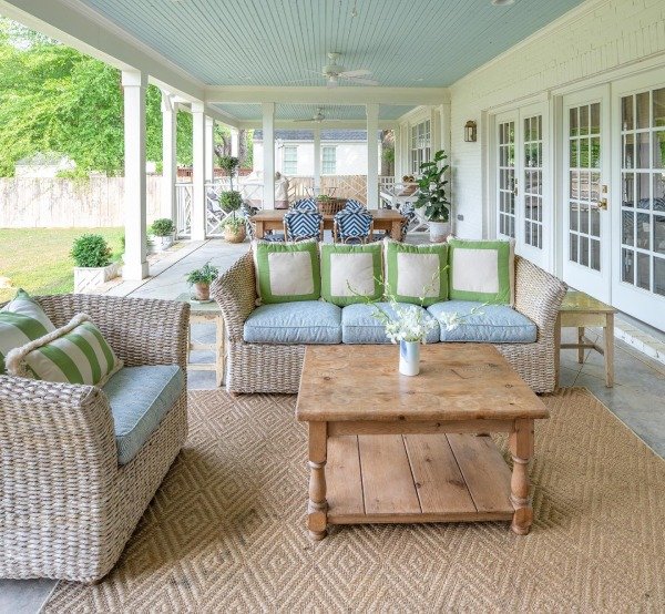 A porch swing with floral cushions and a small side table holding a potted plant.