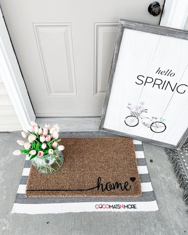 A wooden sign with the words “Hello Spring”