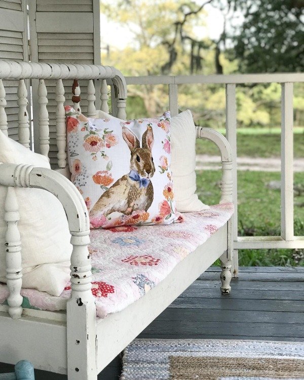 A cozy porch seating area with pastel-colored cushions and a light blue throw blanket.