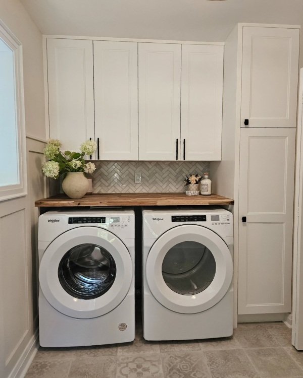 Laundry room decor, A smooth countertop sits above front-loading washer and dryer units. It creates a clean folding station and hides gaps between appliances.
