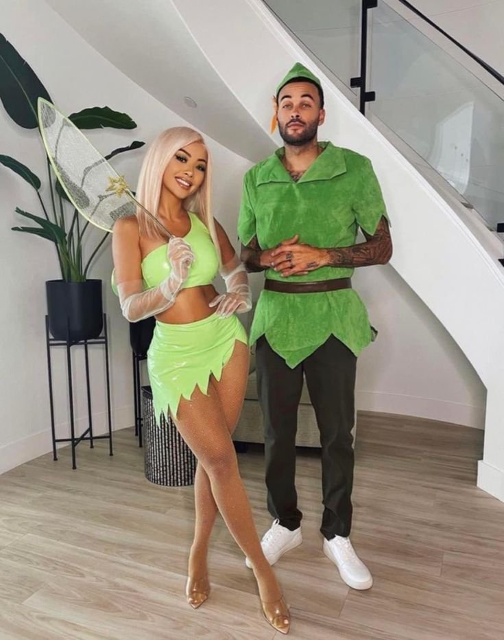 A whimsical Halloween look with a Black couple dressed as Peter Pan and Tinker Bell. Their costume features wings, green outfits, and a touch of pixie dust for magical vibes.