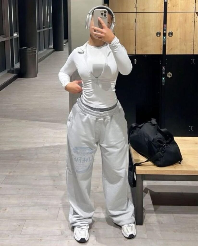 A woman wearing a white long-sleeve top and matching sweatpants