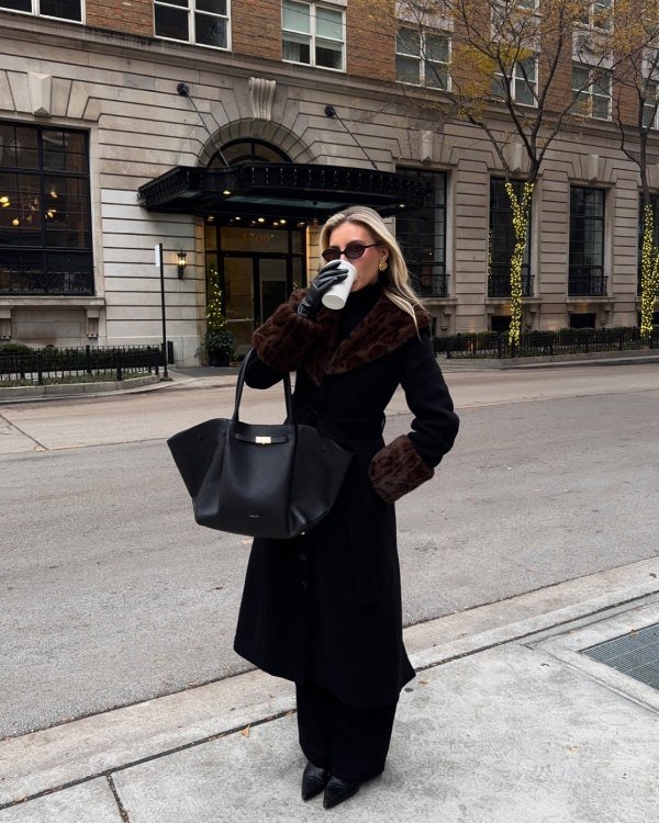 Woman wearing lassy winter outfit faux fur coat. Outfit all black while drinking coffee.