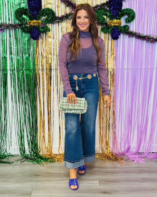 Trendy Mardi Gras outfit with denim pants paired with a sheer top and statement accessories.