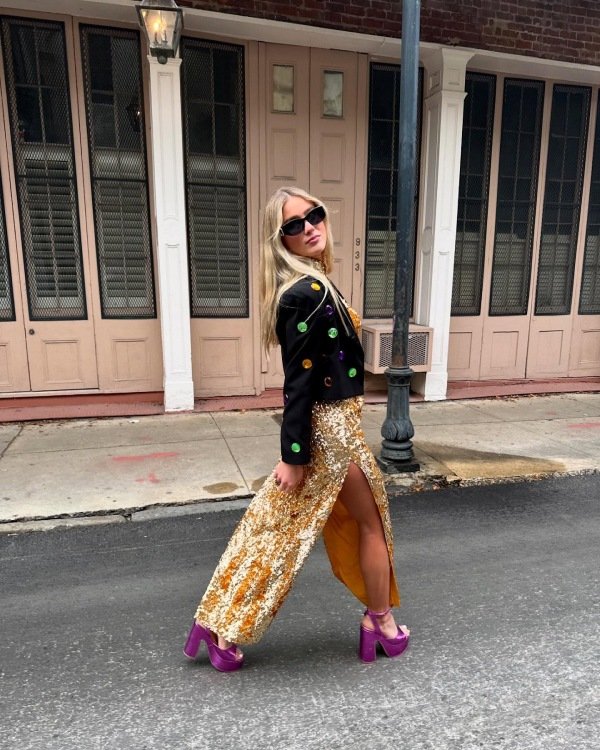 Mardi Gras outfit with a decorated jacket paired with a gold sequin maxi skirt and festive accessories.