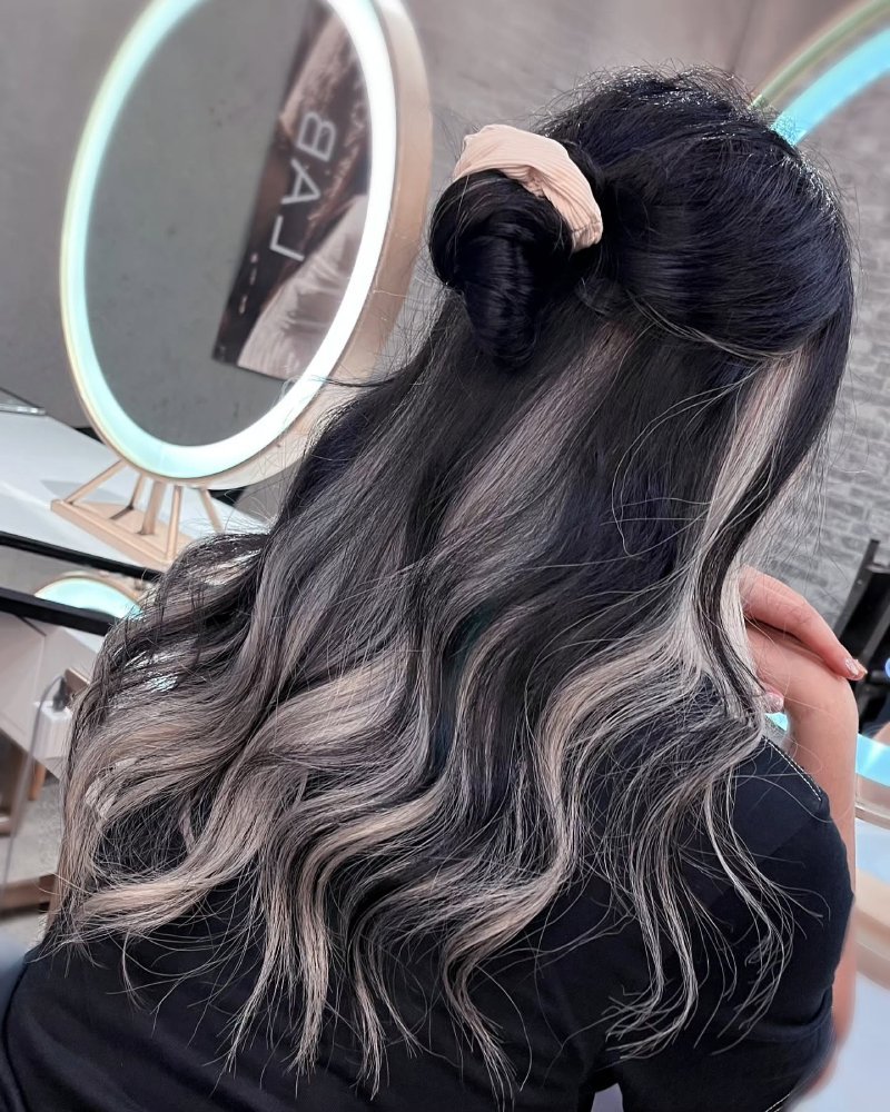 Medium brown hair with warm caramel peekaboo highlights subtly visible beneath layered strands.