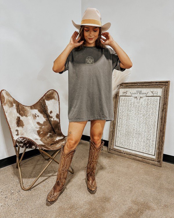 Country concer summer outfit ideas for women. Womanw earing a grey t shirt, western boots and cowboy boots