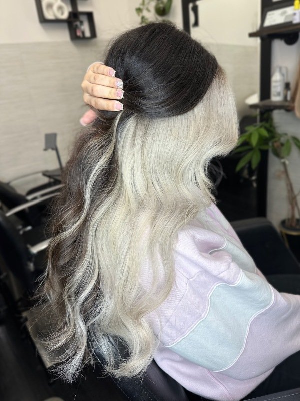 Jet black hair with icy blonde peekaboo highlights underneath, styled sleek and straight.