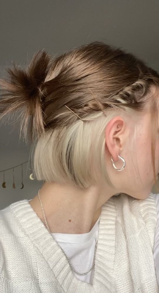 Short bob haircut with hidden blonde peekaboo highlights revealed when hair is tucked behind the ear.