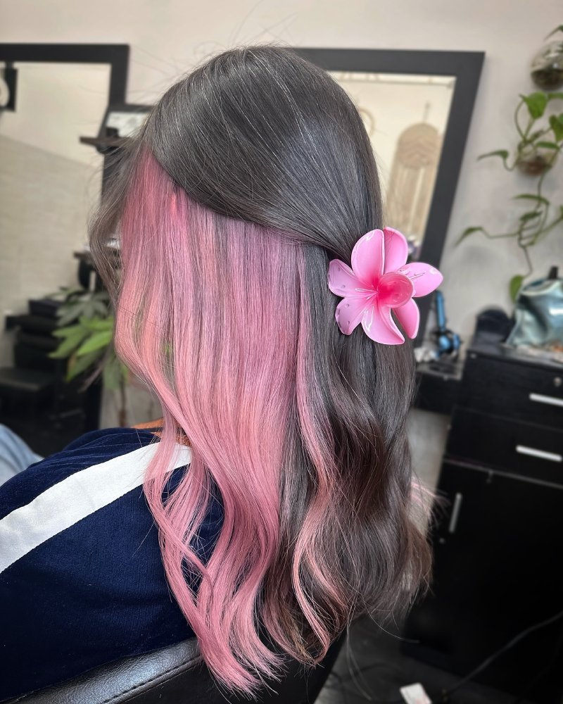 Dark brunette hair with hidden blonde peekaboo highlights underneath, styled in loose waves to reveal contrast.