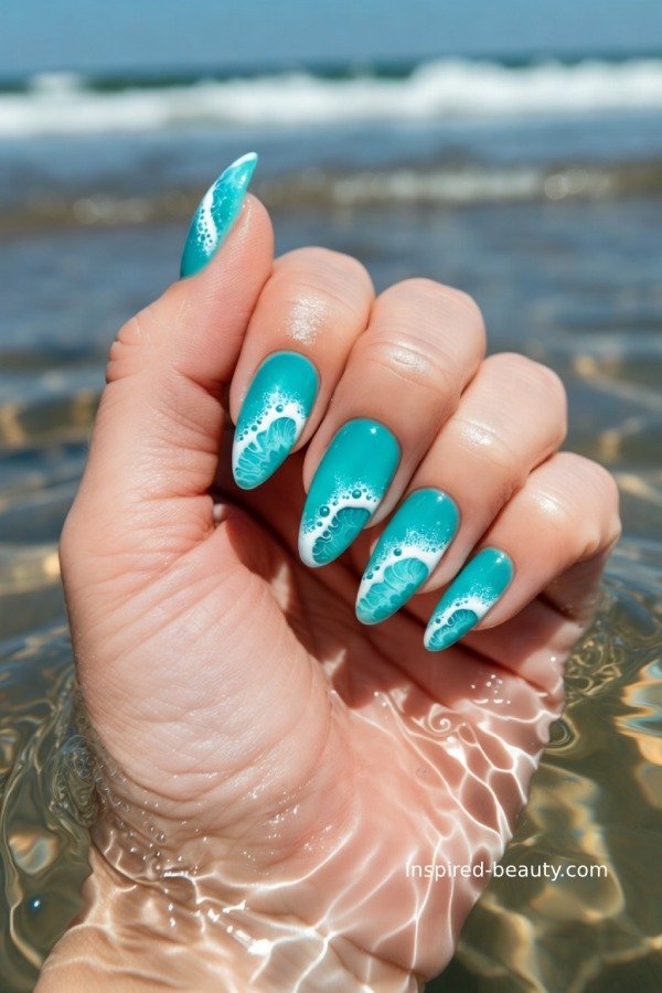 Blue ocean-inspired nails with wave designs and white accents, glossy beach manicure.