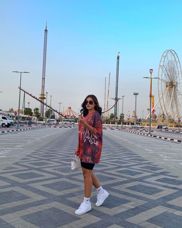 Girl wearing oversized hoodie with bike shorts and white sneakers for a casual back-to-school outfit.