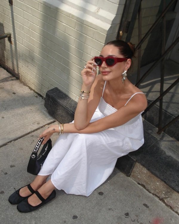 Woman wearing a white linen dress with black ballets and a sunglasses on a tropical Hawaii vacation.