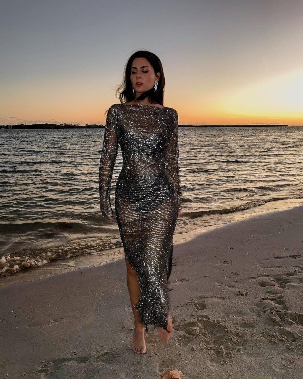 Woman wearing a shimmer sunset dinner dress with sandals for an elegant Hawaii vacation evening look.