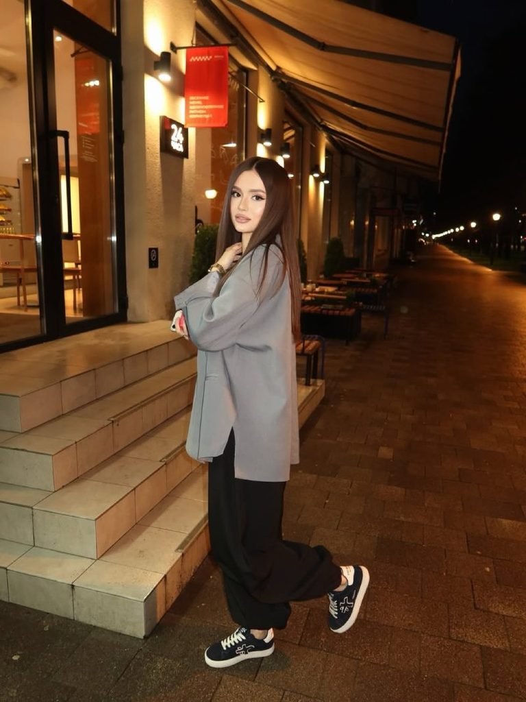 Woman wearing a structured blazer over a fitted top with black sweatpants and sneakers for an elevated casual outfit.