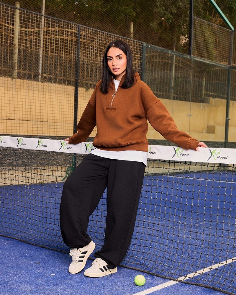 Woman styling black sweatpants with a colorful fitted top, casual sneakers, and a shoulder bag for a bold everyday look.