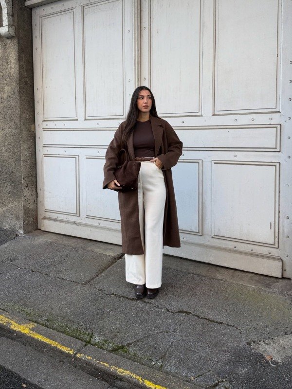 Chocolate brown trench coat styled with cream trousers, a brown sweater and brown ankle boots.