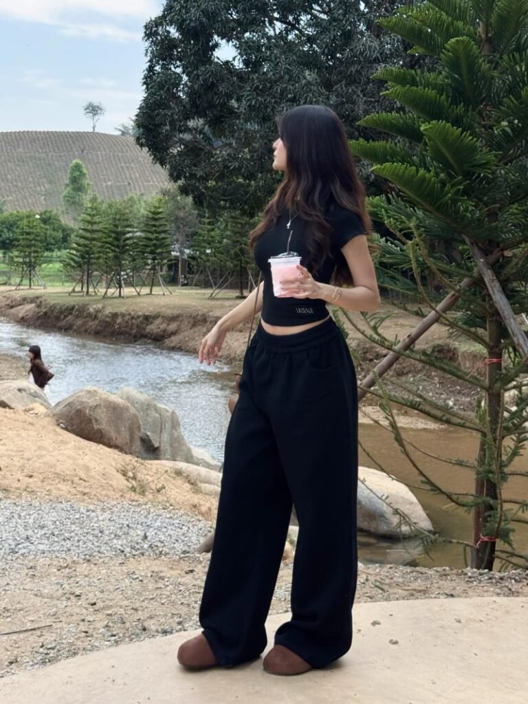 Woman wearing a fitted black top with matching black sweatpants and simple accessories for a sleek monochrome casual outfit.
