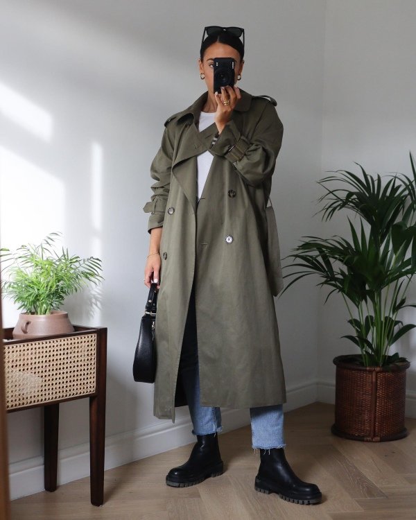 Olive green trench coat outfit with blue jeans, white top and warm brown accessories.